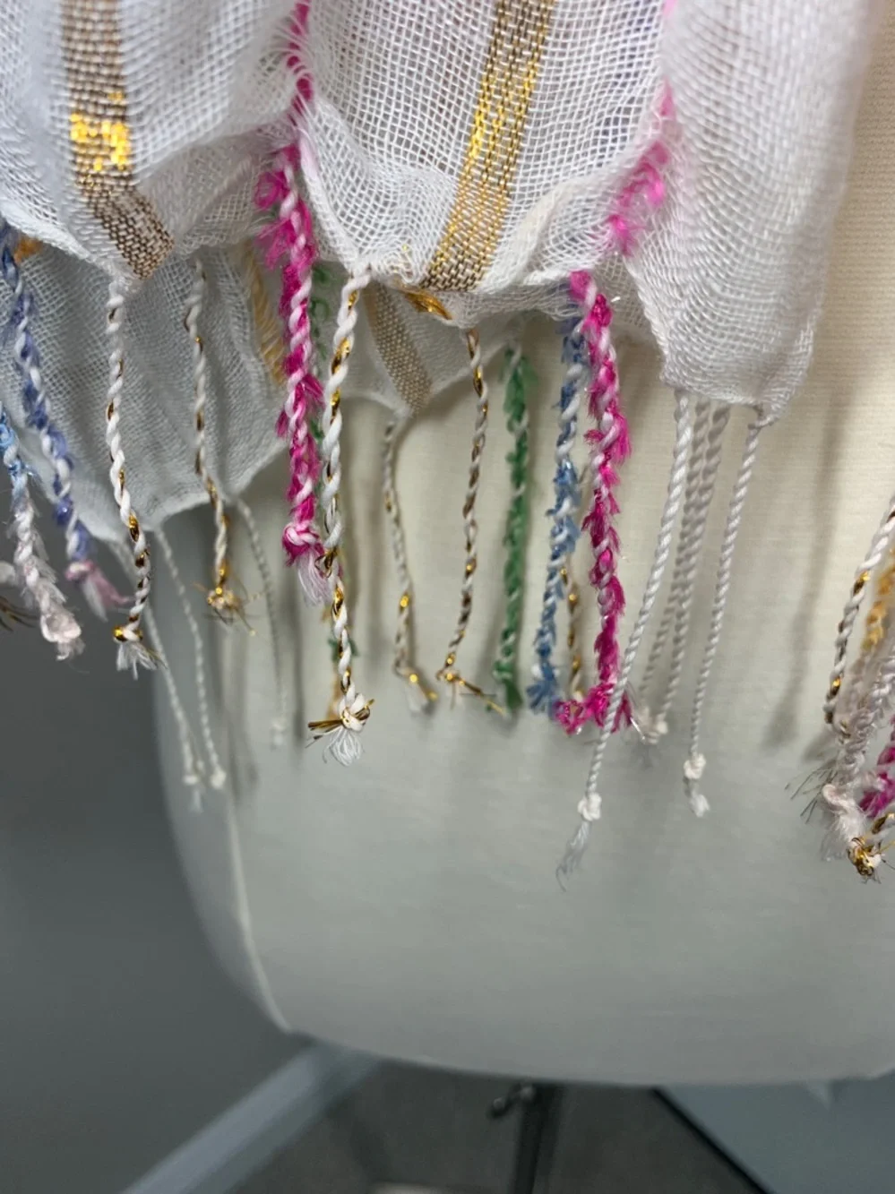 White, metallic gold, pink, blue, and green scarf with fringe